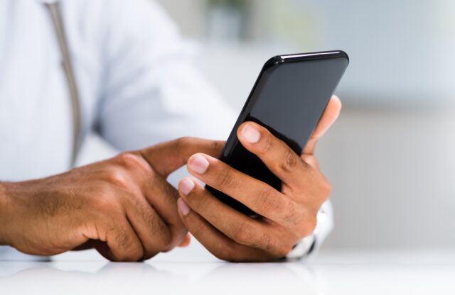 african,man,holding,smartphone,or,mobile,phone