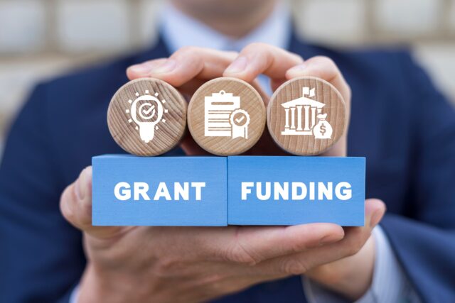 man,holding,colorful,blocks,with,icons,and,inscription:,grant,funding.